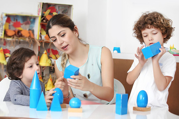 Montessori teacher demonstrating Montessori materialsto students in a Spanish bilingual preschool classroom